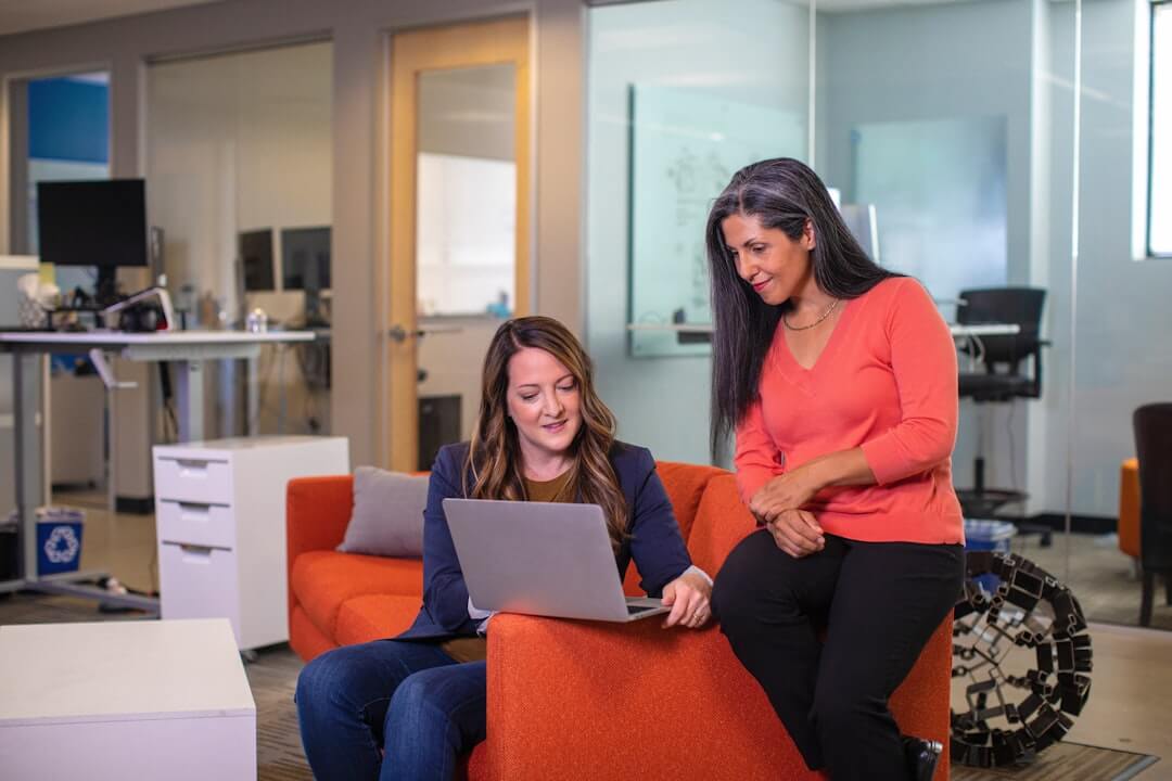 Photo by LinkedIn Sales Solutions two women sitting on a couch looking at a laptop